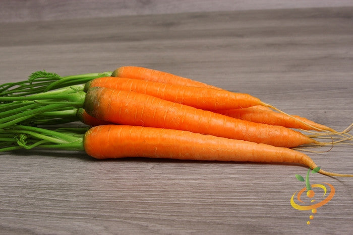 Fresh 7-inch long Tendersweet carrots with green tops on wooden surface